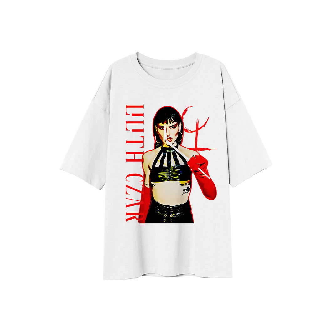 White tshirt on a white background. On the side of the shirt is the lettering lilith czar going down the shirt in red. The center of the shirt features a photo of lilith standing wearing a black top and black pants with red gloves holding a match to her face. Next to her head is the L C symbol logo.